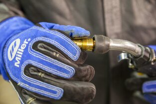 Closeup of welder's gloved hand tightening a gas diffuser