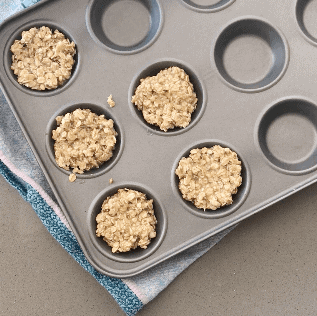 Adding the Flapjack Easter Nests mix to the cupcake tin.