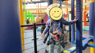 トンデミ平和島キッズエリアで、白いヘルメットとハーネスを装着し、ロープウォークに挑戦する子供