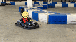 屋内コースのカーブを曲がる子供用のEVカート。トムス社製の本格的なマシンを運転している様子