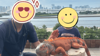 お台場の景色を背景に、アニミルの看板動物である巨大イグアナと一緒に記念撮影をする親子