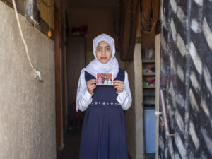 Hana, 14, holds up a photo of herself with the family members who were lost in an airstrike, Gaza