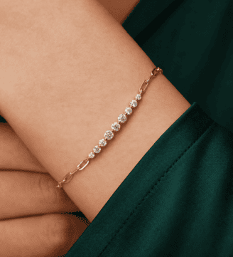 GLAMAVERA Kessane gold-plated moissanite tennis bracelet worn on the wrist with an elegant green sleeve