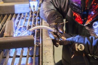 Closeup of MIG gun welding on part on table