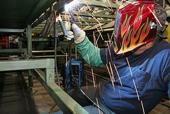 Image of a welder with arm welding above their head