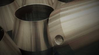 Casquillos cónicos de acero pulidos y mecanizados en torno CNC con agujero pasante limpio en el taller mecánico.