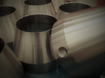 Casquillos cónicos de acero pulidos y mecanizados en torno CNC con agujero pasante limpio en el taller mecánico.