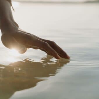 Stages Of Grief: Acceptance: A hand touches water with light behind it