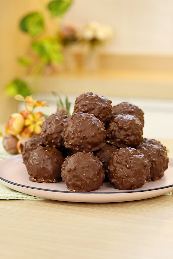 Prato branco com bombons crocantes de wafer cobertos por chocolate, sobre fundo desfocado.