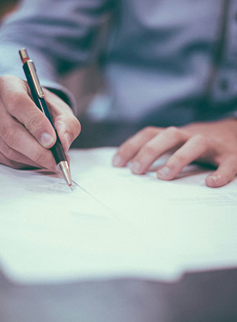 A person fills out documents while holding a pen.
