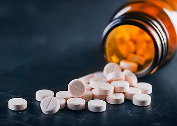 Pills spilling out of a bottle on a table