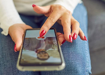 Close-up of a woman using a smartphone to take a photo of herself, showcasing social media interaction and digital psychology concepts.