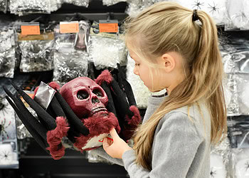 Halloween costume skull mask with red fur, girl shopping for spooky accessories at a store, Halloween decorations and masks, horror-themed costume ideas, festive costume shopping for Halloween.
