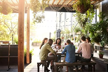 Coworkers gather for after-work cocktails beneath a pergola on the patio of a luxury Raleigh office tower