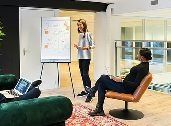 pexels-photo-1647919-1647919 Three adults engaged in a casual office meeting with laptops and a flipchart.