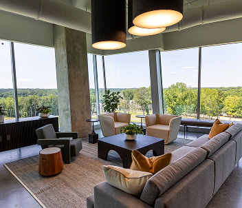A modern lounge area with couches and natural lighting invites comfortable coworking in a Raleigh office building.