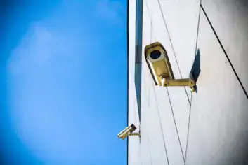 Security camera mounted on the corner of a building against a blue sky