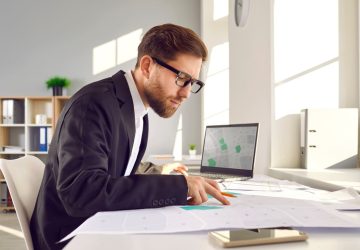 DOCFA, uomo a lavoro con documenti catastali e pc