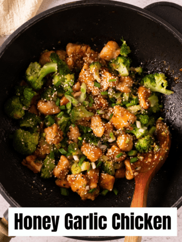 Stir-frying honey garlic chicken and broccoli in a wok with a wooden spatula.