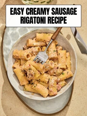 A bowl of creamy Sausage Rigatoni topped with grated parmesan cheese with a text overlay reading