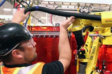 Operator replacing power cable on a through-arm robot