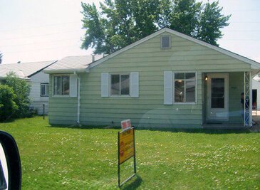 yellow single family home with for sale sign in lawn