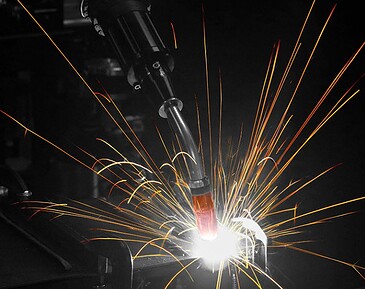 Closeup of through-arm robotic MIG gun welding with sparks