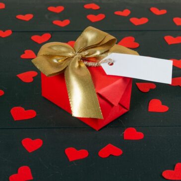 a red gift box with a gold bow and a white card
