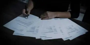 Hands reviewing multiple pages of a commercial contract on a dark desk — penalty clause under Article 551 of the Ukrainian Civil Code