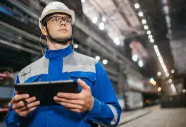 Decorative image for blog post on the importance of cybersecurity for manufacturers and warehouses in Chicagoland. Image depicts man with an ipad in a large warehouse in work clothes.