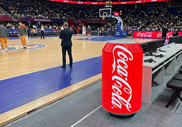Can-shaped creative LED screen branded as Coca-Cola standing courtside at a basketball arena in the United States