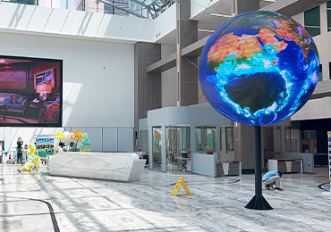 Large spherical LED display ball showing a glowing Earth globe in a modern atrium lobby in Kuwait