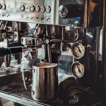 High-end espresso machine with milk frothing pitcher in a coffee shop, showcasing professional coffee gear.