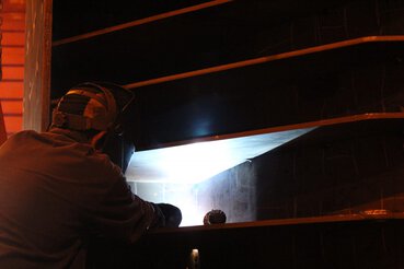 Over-the-shoulder view of welding operator welding on large piece of equipment