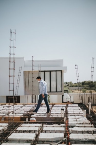 A modern residential building under construction with a person inspecting the site.
