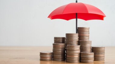 czerwony parasol nad stosami monet