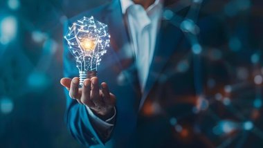 mżczyzna w garniturze trzymający w dłoni wirtualny obraz żarówki