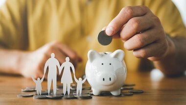 skarbonka, człowiek wrzucający monetę, sylwetki rodziców i dzieci