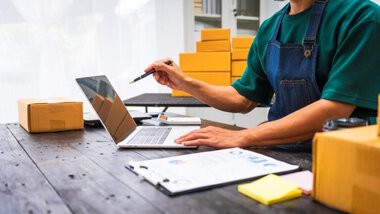 pracownik firmy kurierskie, magazyn, paczki, laptop, dokumenty