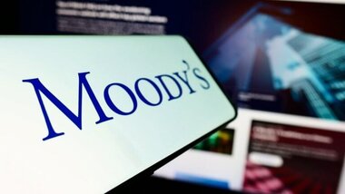 logo Moody's na smartfonie, w tle budynki
