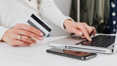 laptop, kobieta z kartą w dłoni