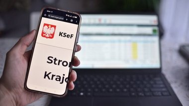 smartfon ze stroną KSeF, w tle laptop