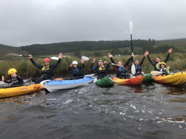 Group of all ages kayaking at sunset in Dunlewey Lake