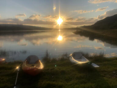 Dunlewey Lake at sunset with empty canoes in foregound
