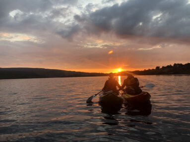 A couple kayaking at sunset in Dunlewey Lake
