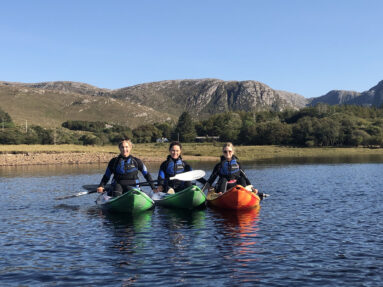 A young group kayaking at sunset in Dunlewey Lake