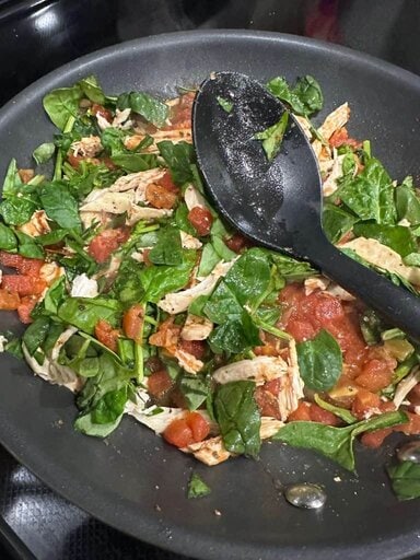 Sauteing spinach, diced tomatoes and seasoning.
