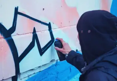 man vandalizing wall with spray paint