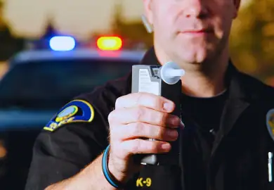 Police officer holding a breathalyzer.