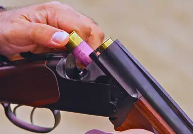 Guy loading ammunition to his shotgun.